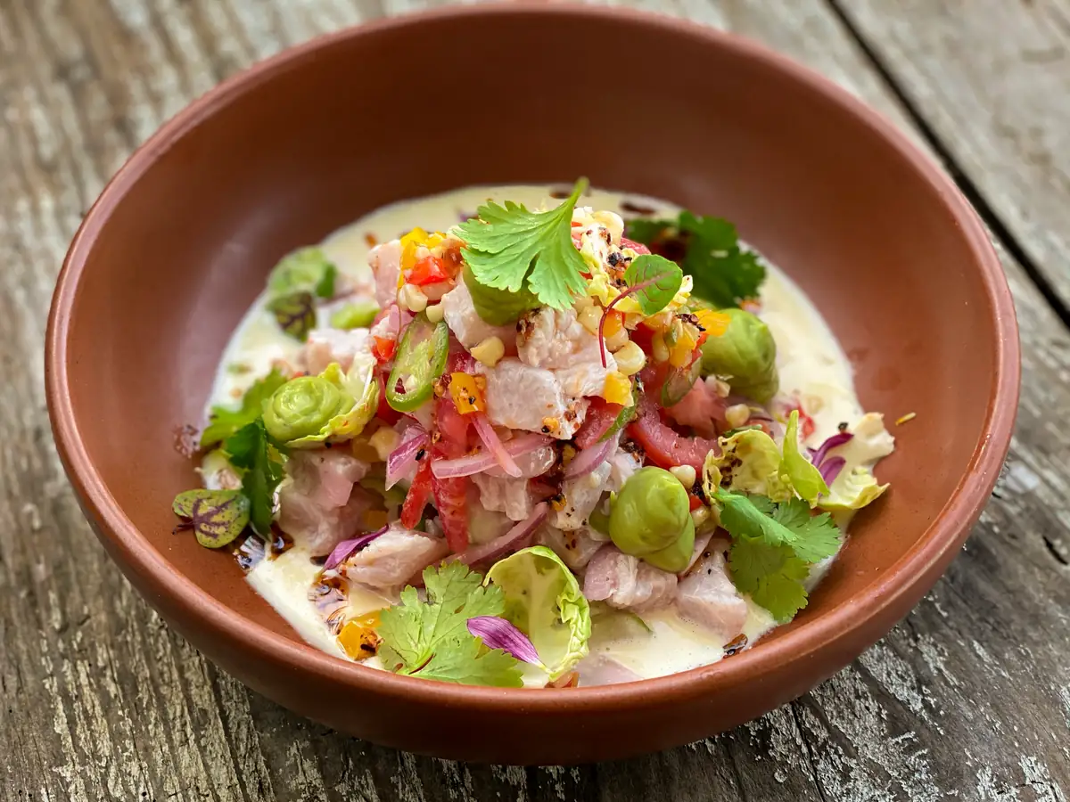 Ceviche served in a shallow bowl on a wooden table at Majahuitas beach club