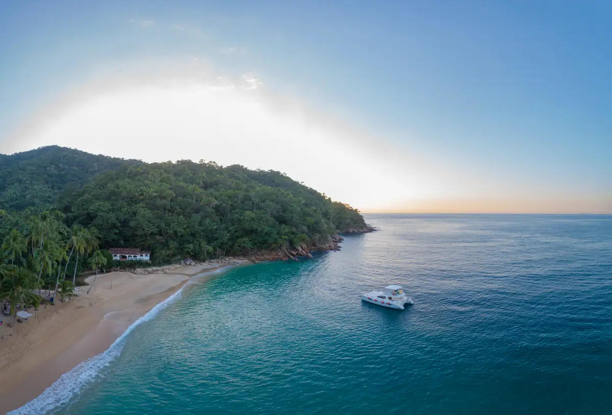 Majahuitas cove at sunset with a boat on flat water and the headland beyond